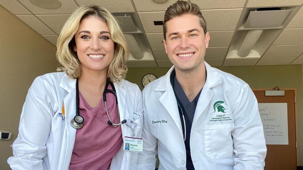 Two people smiling for the camera in lab coats