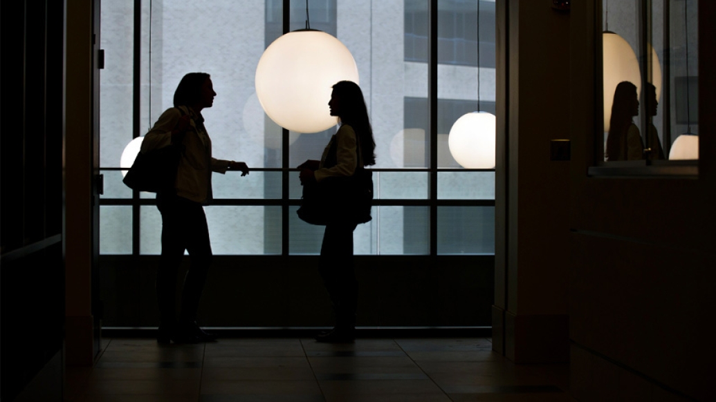 students talking in light silhouettes with light hanging behind shadow looking