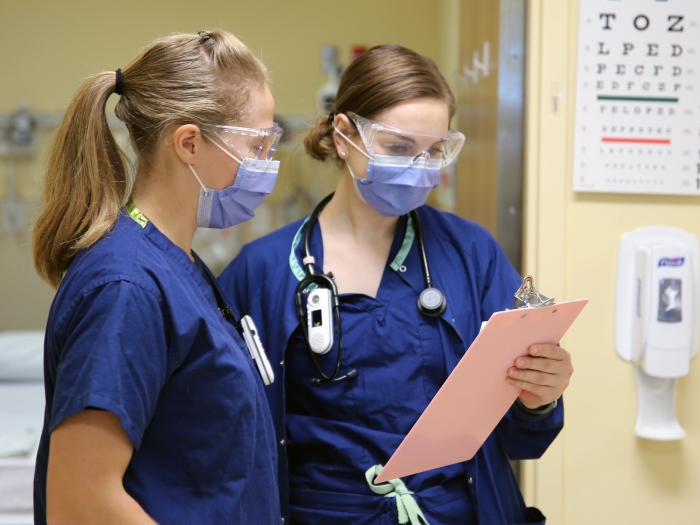 Nurses looking at clipboard with goggles and masks on in clinic