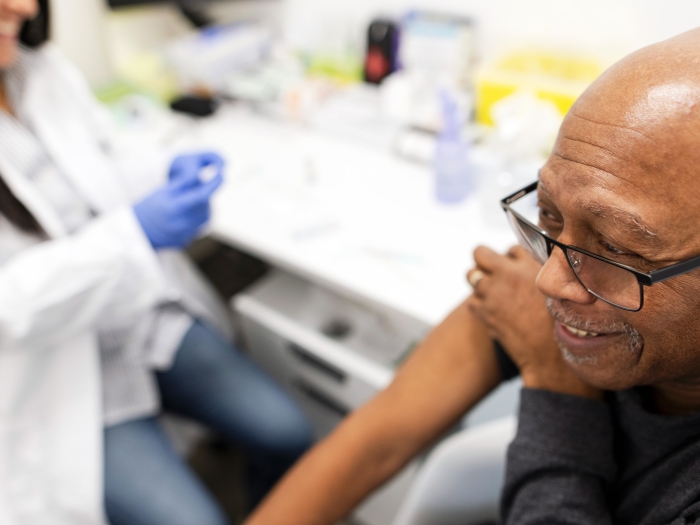 older gentleman getting vaccine arm rolled up