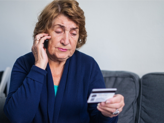 older woman on phone with credit card in hand