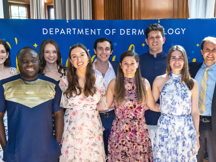 Dermatology Residency Class of 2024 stands in front of "Congratulations" banner