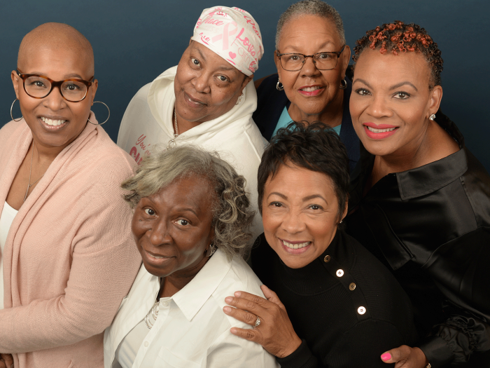 Group photo of six Black women who are breast cancer survivors. They are all looking up at the camera and smiling.