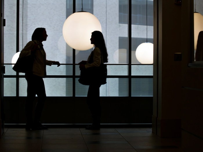 students talking in light silhouettes with light hanging behind shadow looking