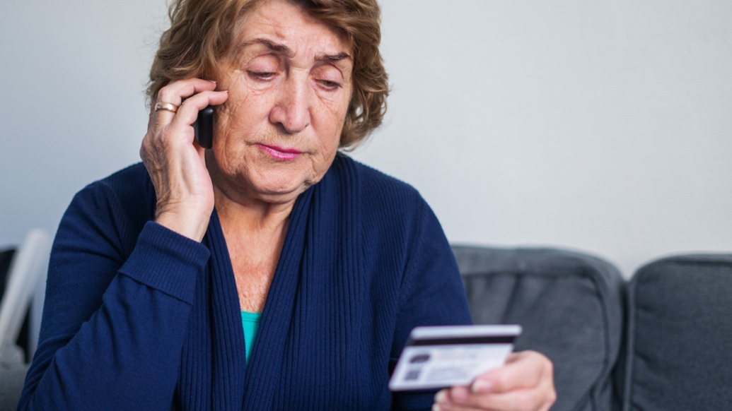 older woman on phone with credit card in hand