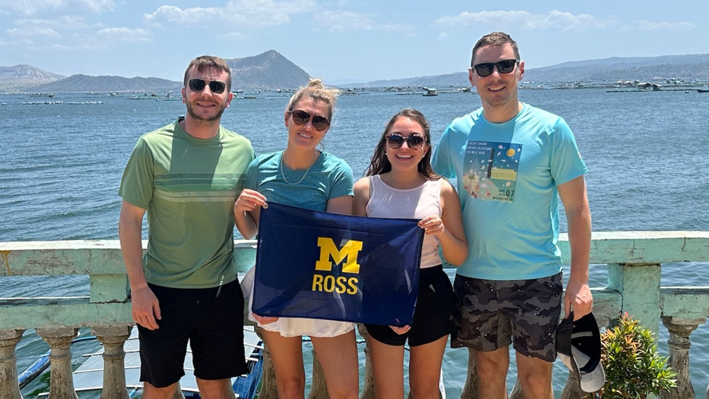 A group of people by water holding a block M sign