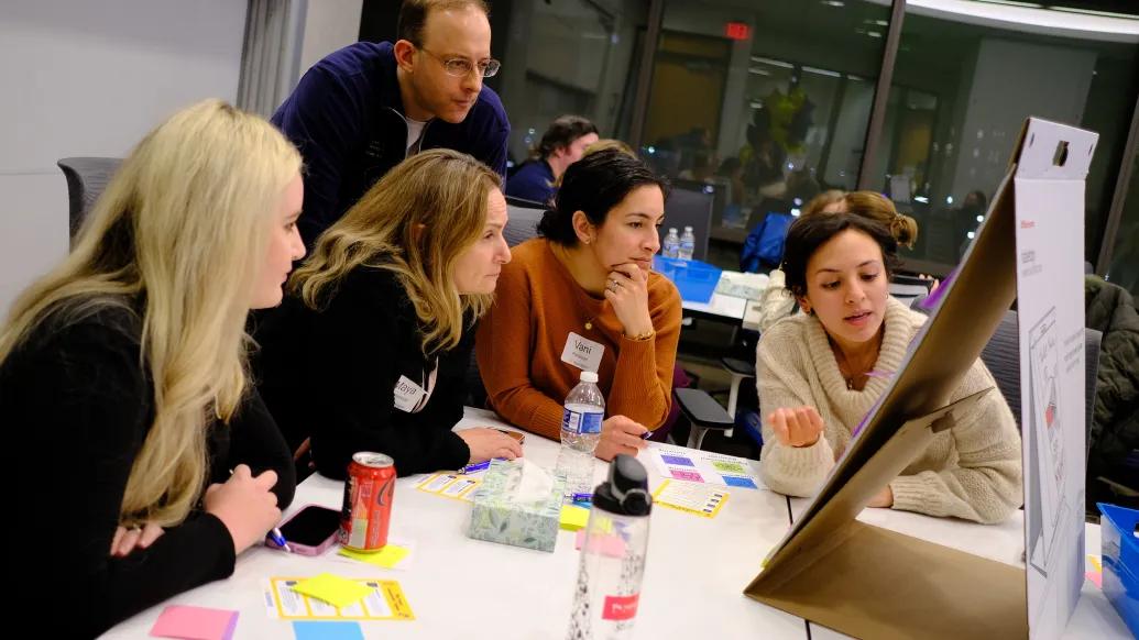 Group of people looking at post-it board.