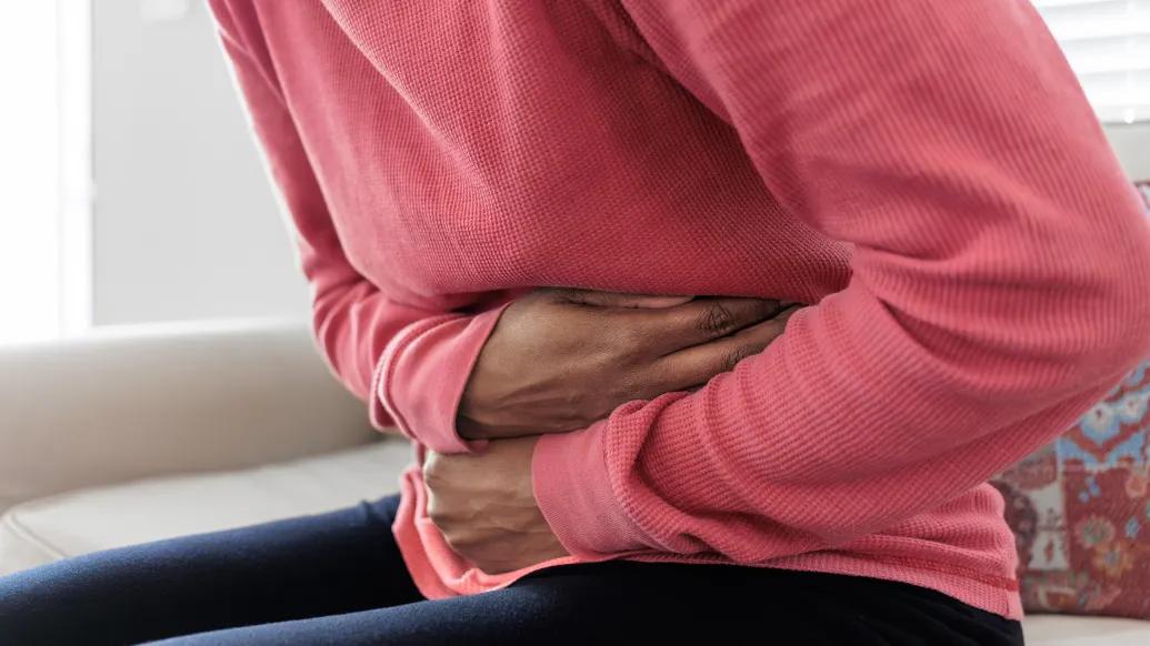 bent over holding stomach pink shirt sitting