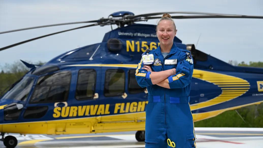 Flight nurse stands in front of a helicopter with arms crossed.