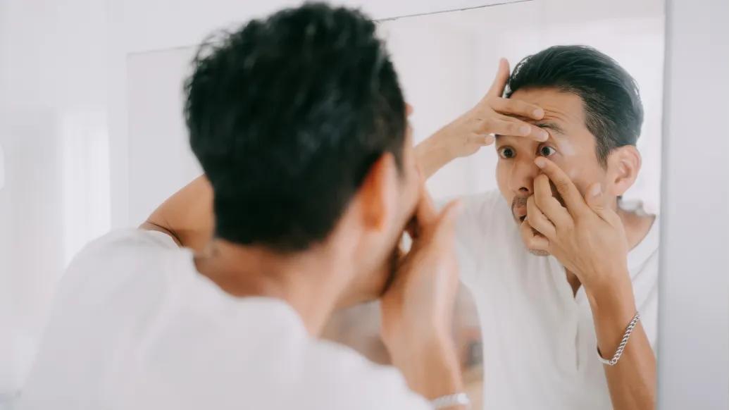 person putting contacts on up close to mirror