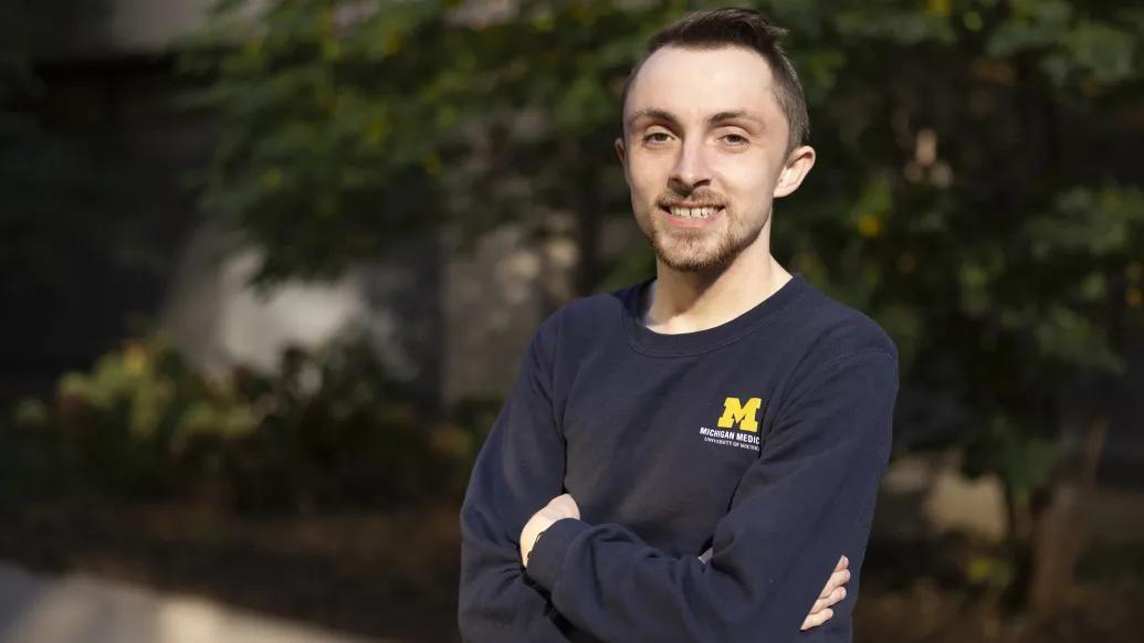 Headshot of Blake Hardin, a man wearing a Michigan Medicine blue long sleeved shirt outdoors