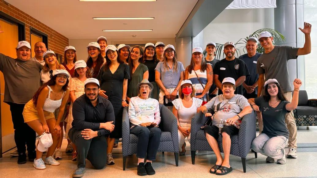 group of people smiling and posing with white hat