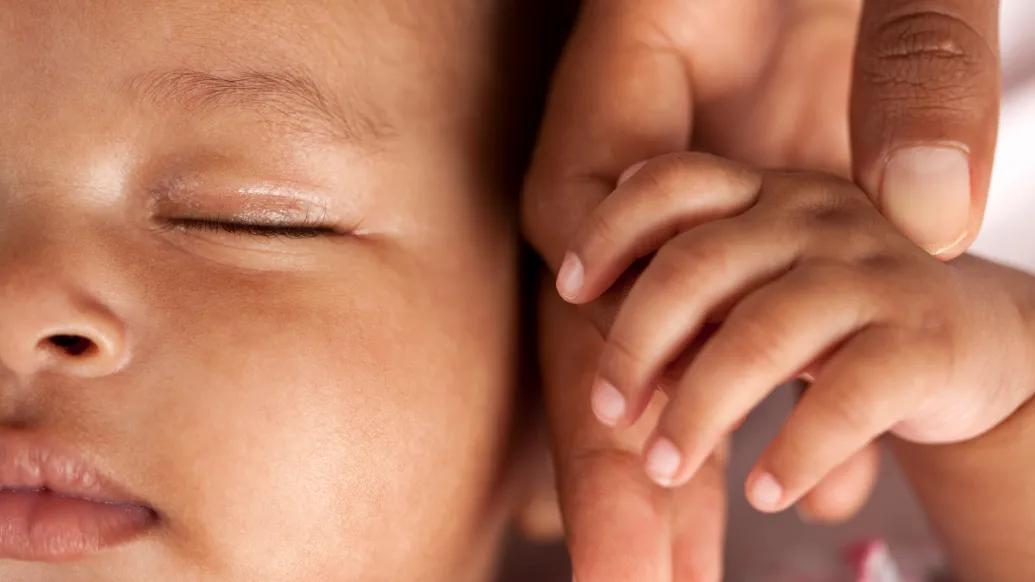 baby close up holding parent's hand