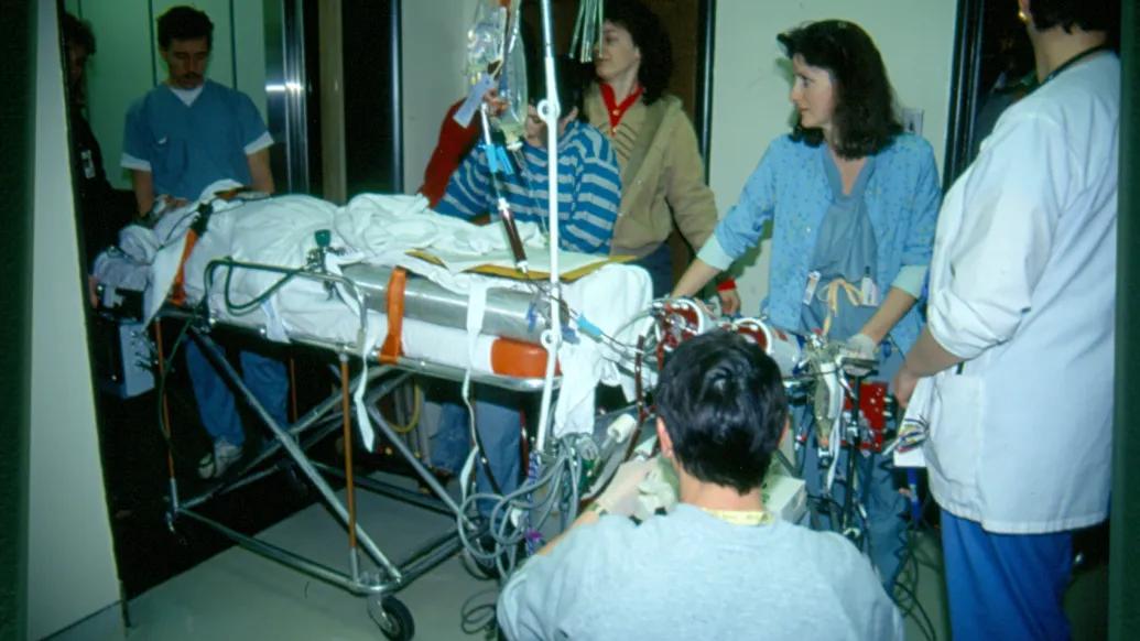 Patient on stretcher taking the elevator with a lot of physicians around