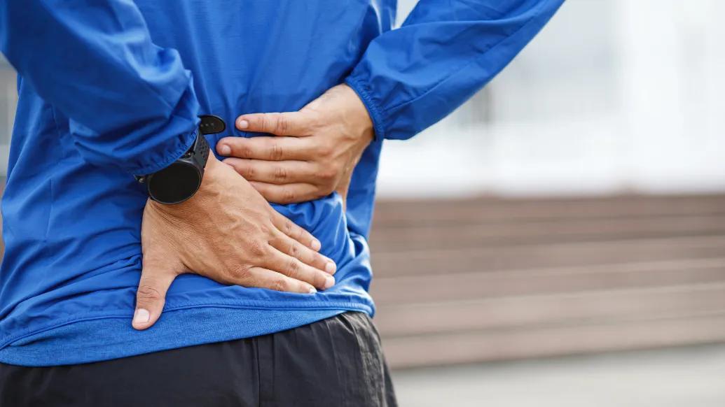 Close-up of person's hands on their lower back