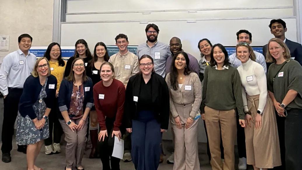 A group shot of student participants and faculty standing in two rows looking at the camera