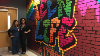 Health care professionals standing in front of a faux graffiti wall in a health center