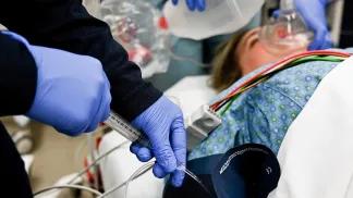 Medical professional using syringe with patient on gurney
