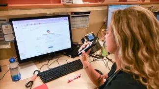 Medical personnel at desk using computer and phone