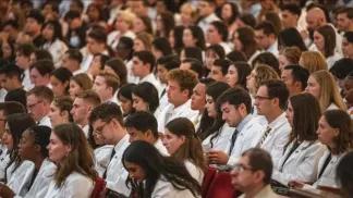 Group of medical trainees in white coats sitting in an auditorium