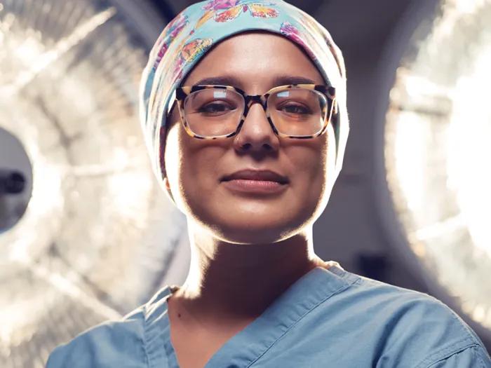 Dr. Valbuena stands in the hospital in her scrubs