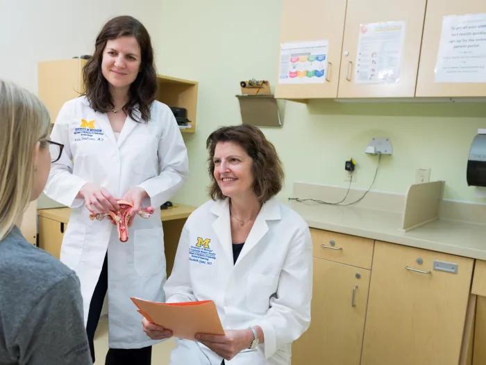  doctor stands with resident to talk to patient 