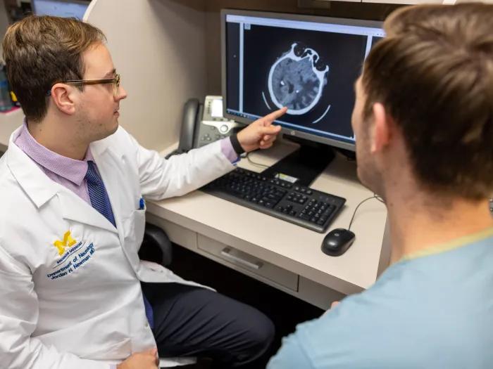 doctor and resident look at scans of the brain on the screen 