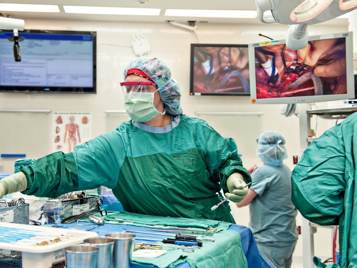 Person in green scrubs is handling surgical instruments in the operating room