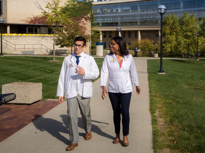 Two people walking outside campus buildings