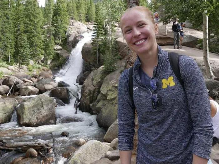 Julie on a hiking trip posing by a waterfall