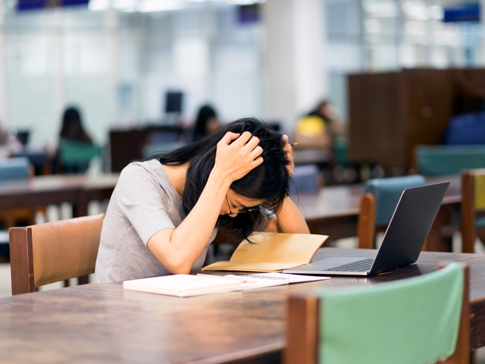 woman holding head down in library
