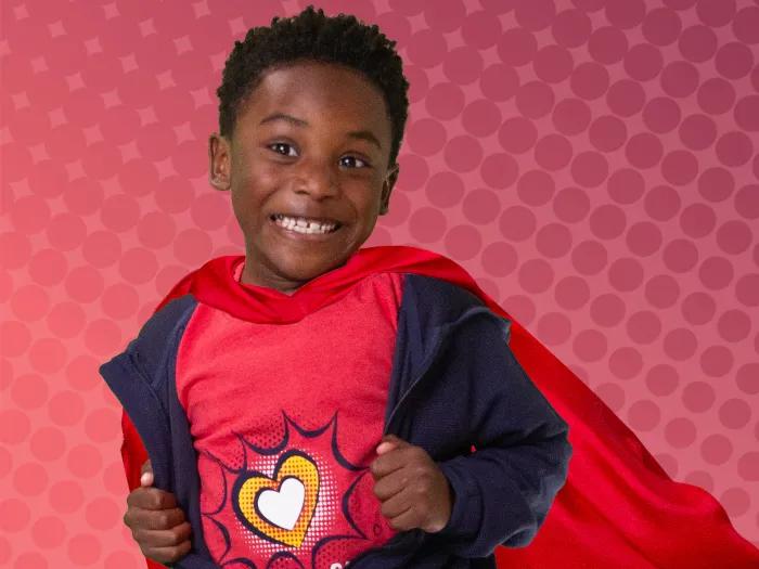 Little boy dressed as a super hero on an comic book background
