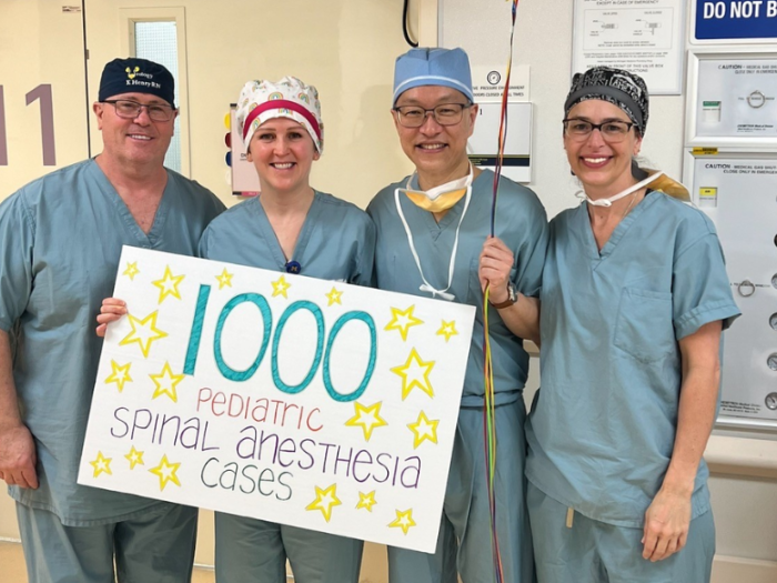 Four people in scrubs hold sign that says "1000 pediatric spinal anesthesia cases"