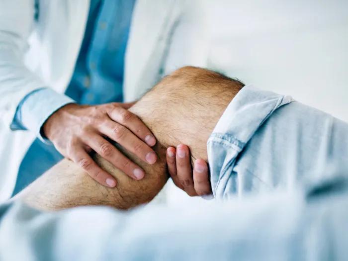 Closeup of knee with caregiver holding the joint and examining it.