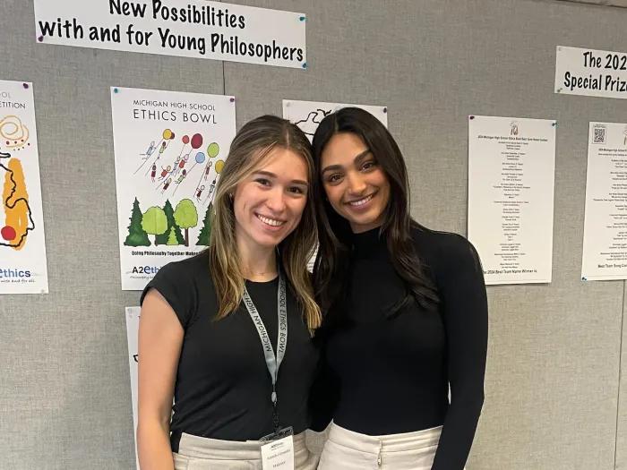Two medical students standing in front of a bulletin board smiling at camera