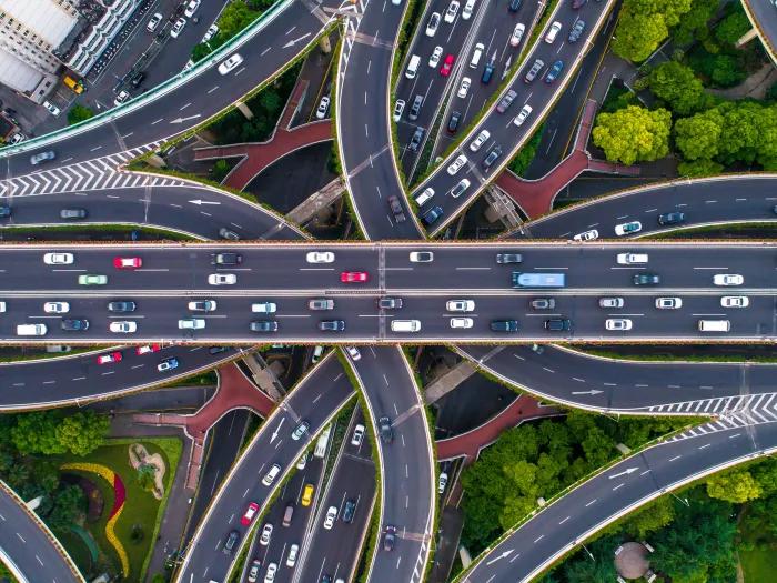 different cars from helicopter view on highways intersecting going all different ways seeing greenery and roads