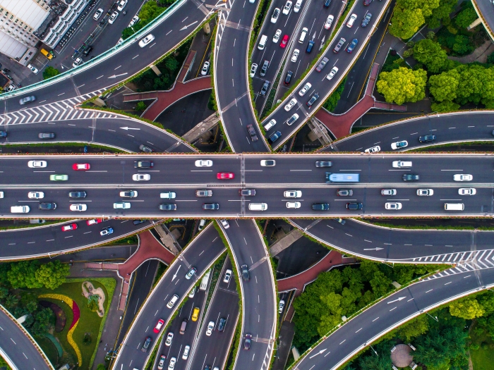 different cars from helicopter view on highways intersecting going all different ways seeing greenery and roads