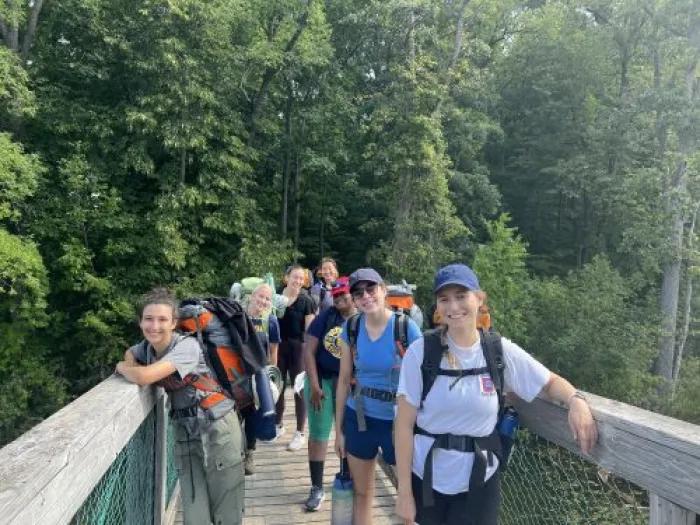 A group of people in hiking gear standing on a walkway in the woods