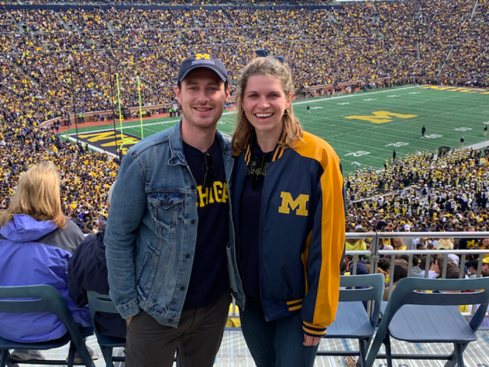 A man and a woman standing next to each other at a football game in the UM stadium