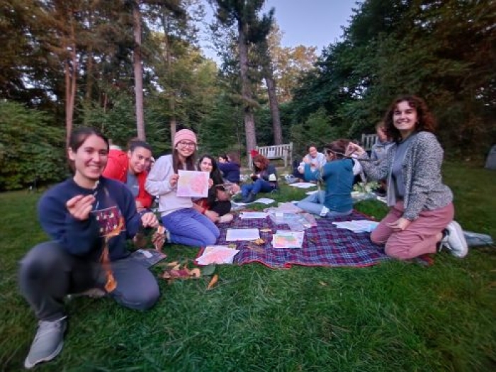 Group of people on a picnic blanket showing their artwork