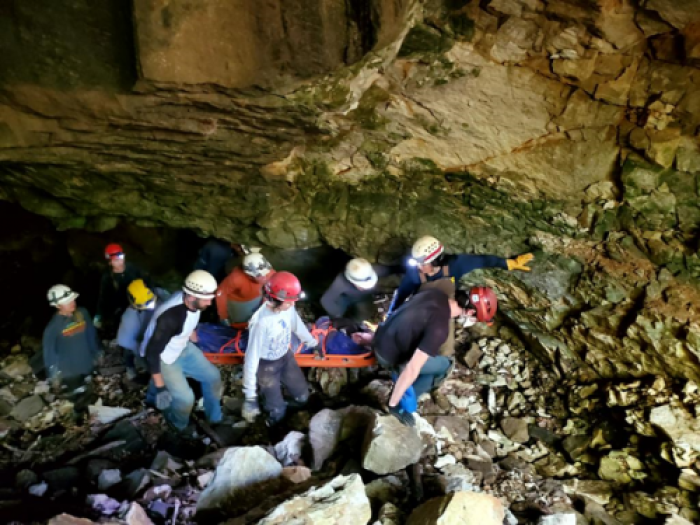 A group of people in hard hats carrying a stretcher out of a cave