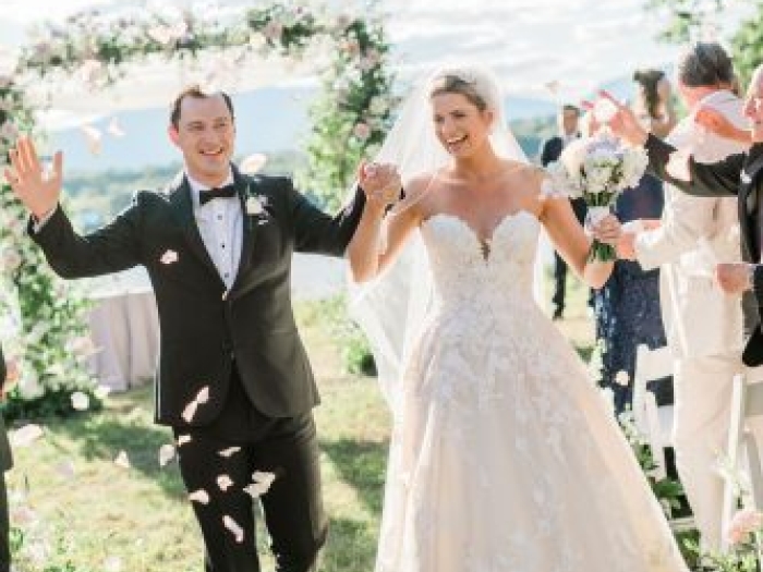 A bride and groom holding hands as they walk down the aisle