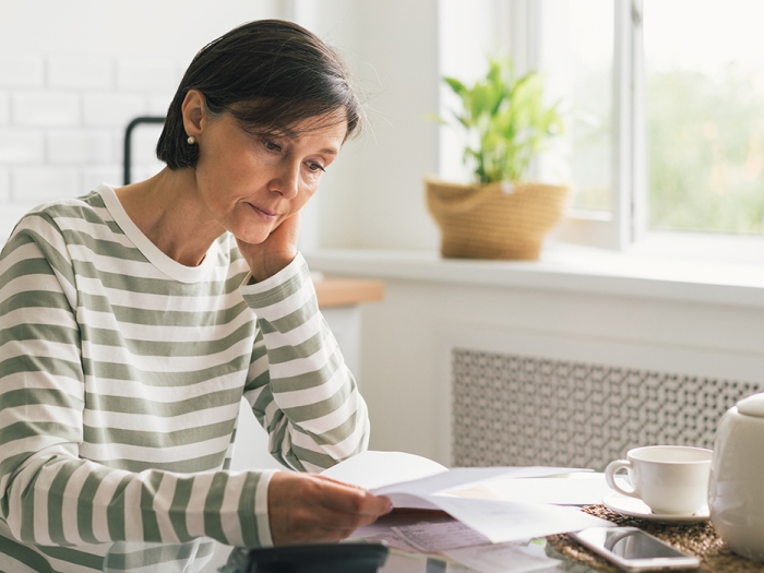 woman sitting at table in stripe shirt stressed seeming white background window