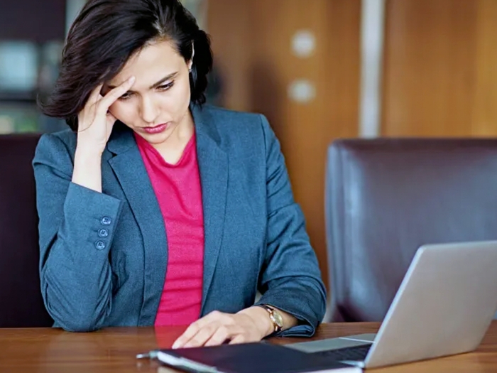 women looking stressed at desk in business suit and laptop and brown conference desk and leather brown chair