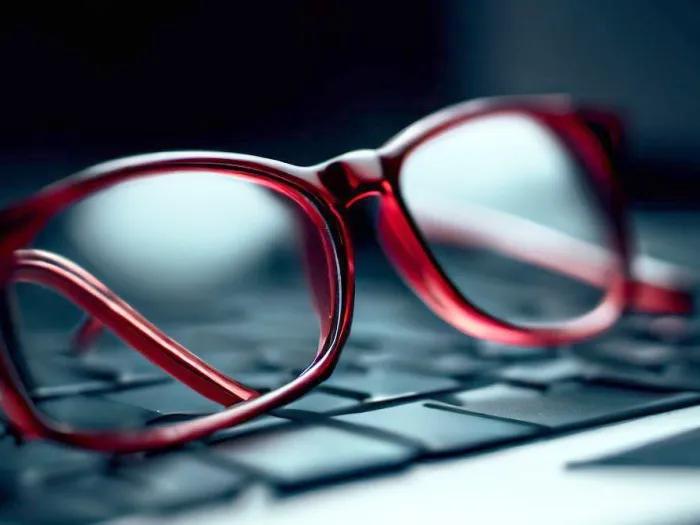 Red-framed spectacles resting on a laptop keyboard