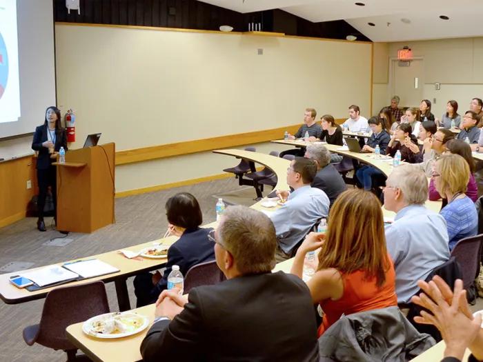 A faculty member presenting to an audience in a lecture hall