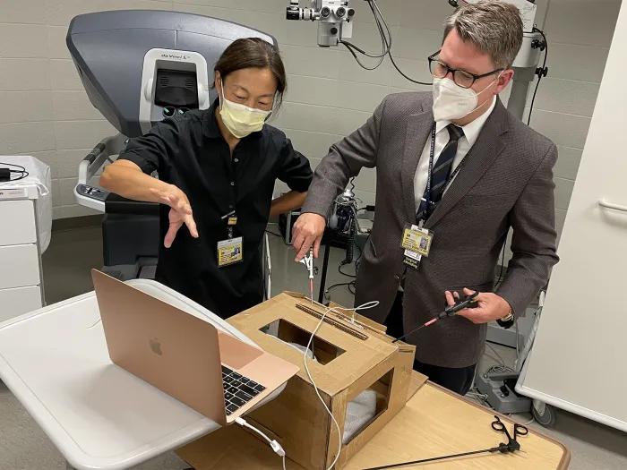 Two people wearing surgical masks testing some wired equipment
