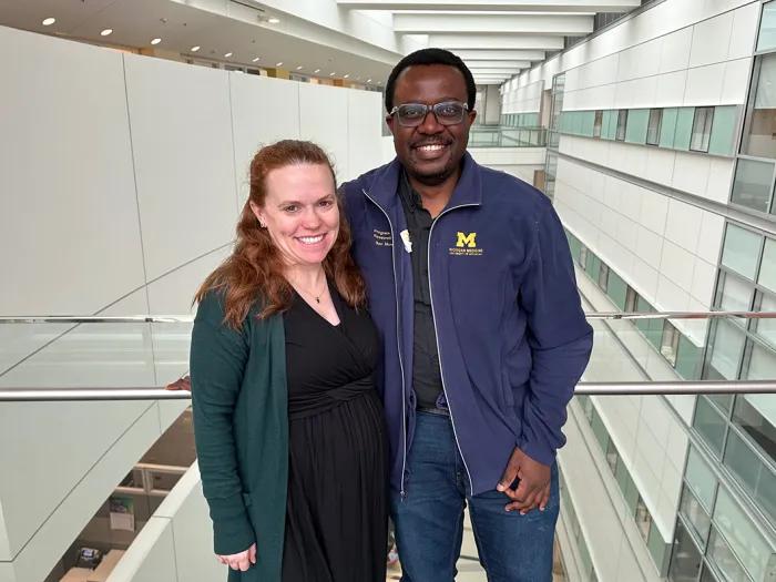 A man and a woman in an office building posing together for a photo