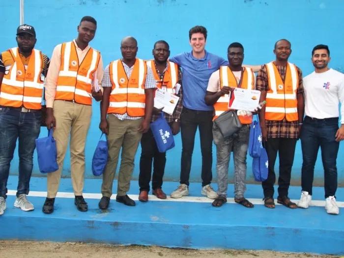 Group of people in neon orange construction vests and two people without posing for a photo