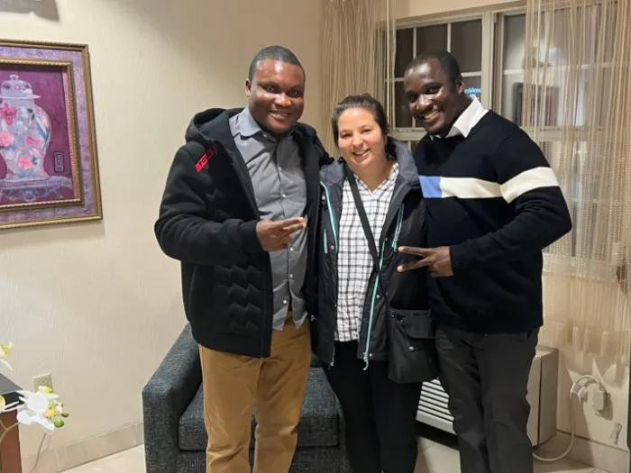 Two men and one woman standing together in a room